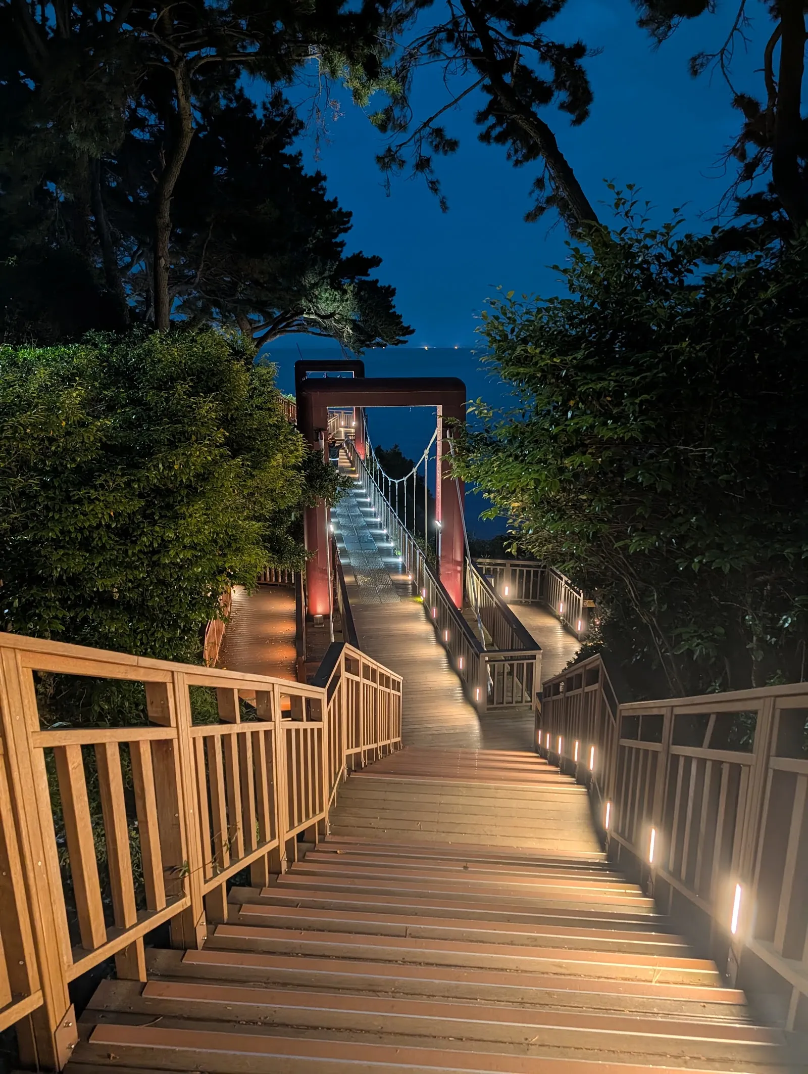 La pasarela de madera iluminada de la isla de Dongbaek al anochecer